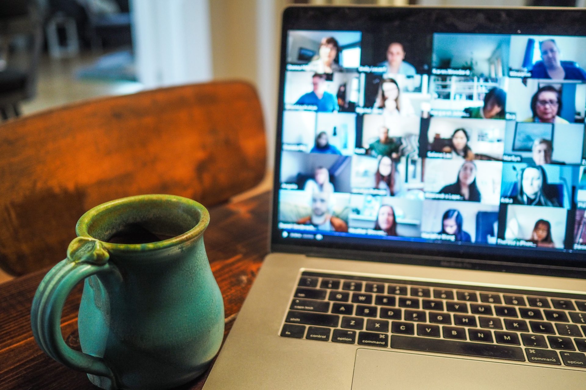 zoom call on laptop screen, with a blue mug next to it on the desk.