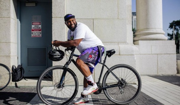 Christopher McGarrell on a parked bicycle, leaning forward and looking over his shoulder