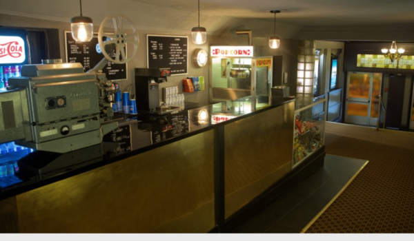 A concession table with a film projector and cash register in a half-lit room.