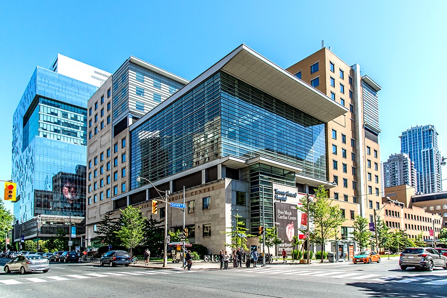 Hospital building on an intersection during a sunny day with blue skies.
