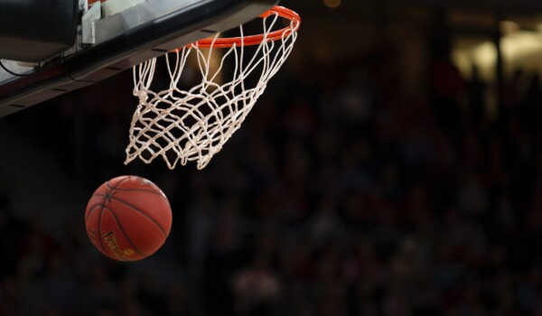 A basketball going through the mesh of a hoop.