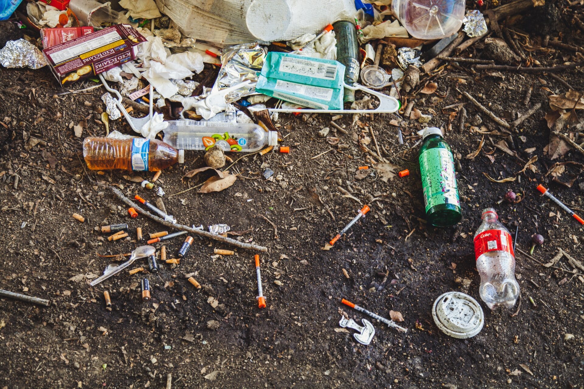 Used syringes scattered on the ground among garbage.